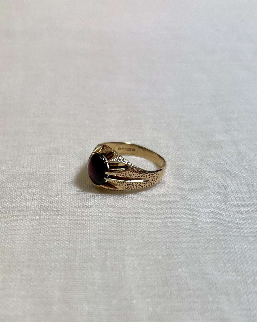 Gold ring with a red gemstone on a white fabric background