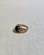 Gold ring with a red gemstone on a white fabric background