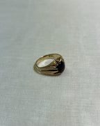 gold ring with dark red gemstone on white fabric background