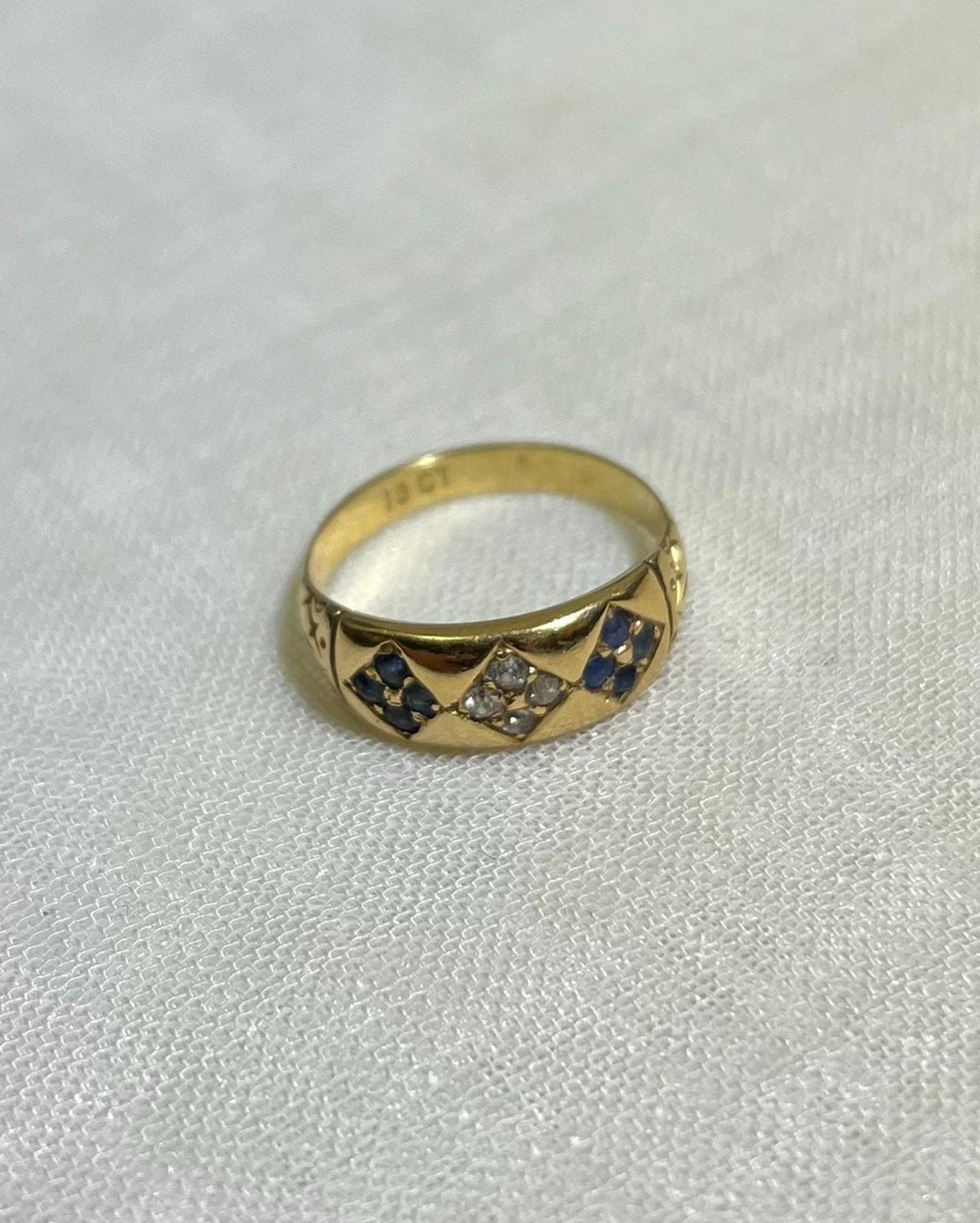 Gold ring with embedded stones on a light fabric background