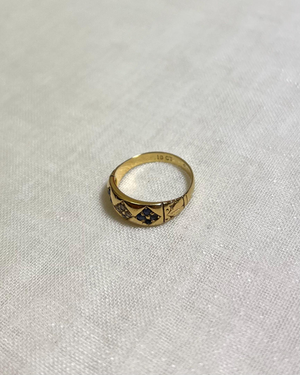 Gold ring with blue stones on a white fabric background
