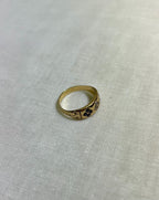 Gold ring with blue embedded gemstones on a white fabric background