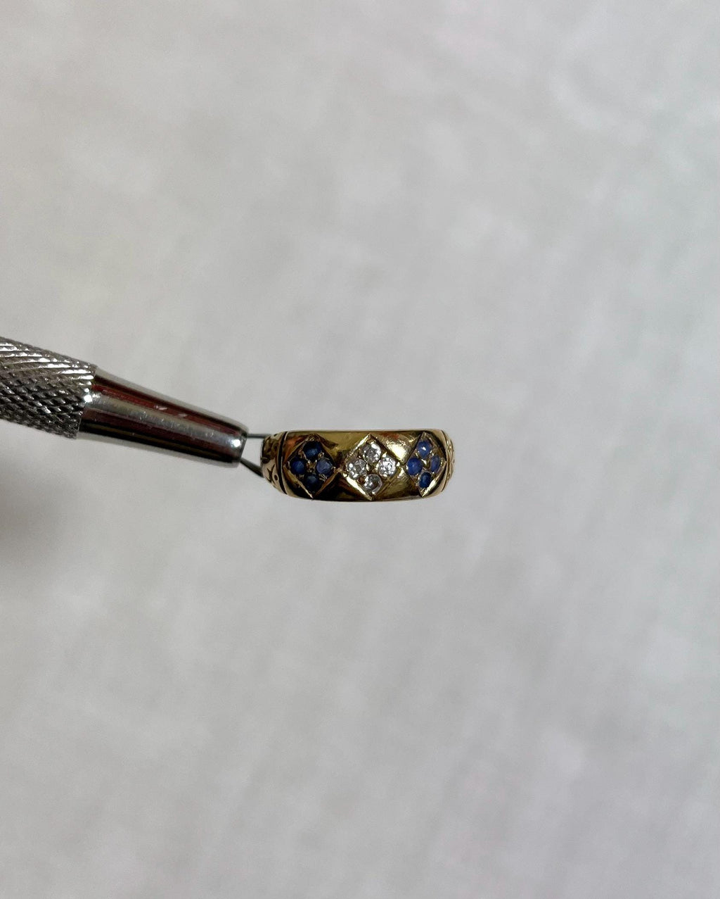 Gold ring with blue and white gemstones on a white background