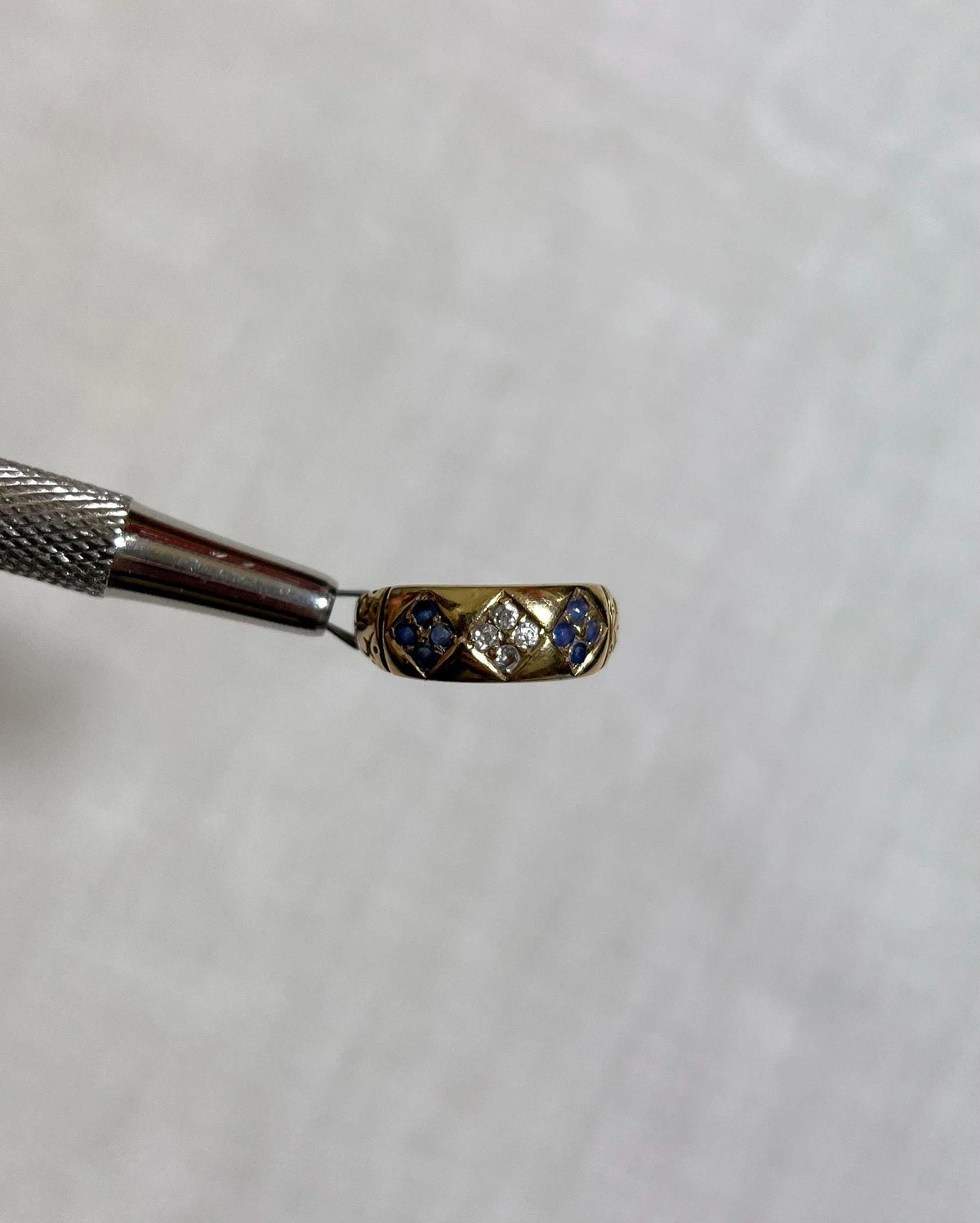 Gold ring with blue and white gemstones on a white background