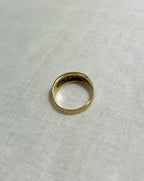 back view of gold ring, resting on white fabric background