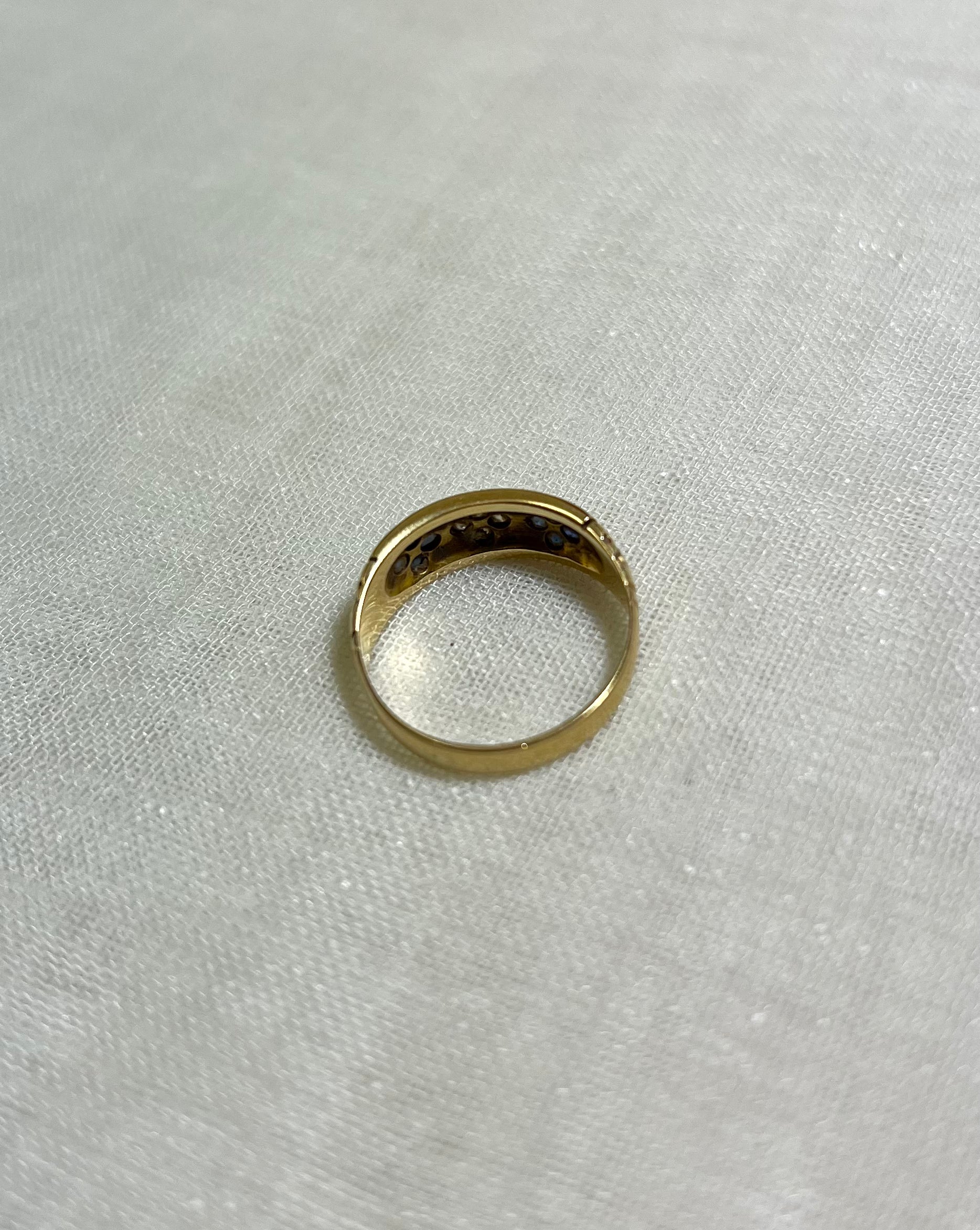 back view of gold ring, resting on white fabric background