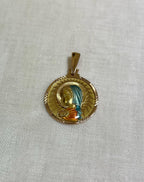 gold disc pendant with enamel Virgin Mary figure, resting on white fabric background