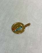 gold disc pendant with enamel Virgin Mary figure, resting on white fabric background 