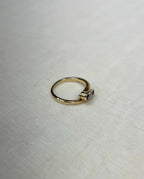 gold ring set with blue and clear stones, resting on white fabric background