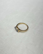 gold trilogy ring with blue sapphires and diamond, resting on white fabric background 