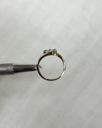 gold ring side view held by metal tool against white background 