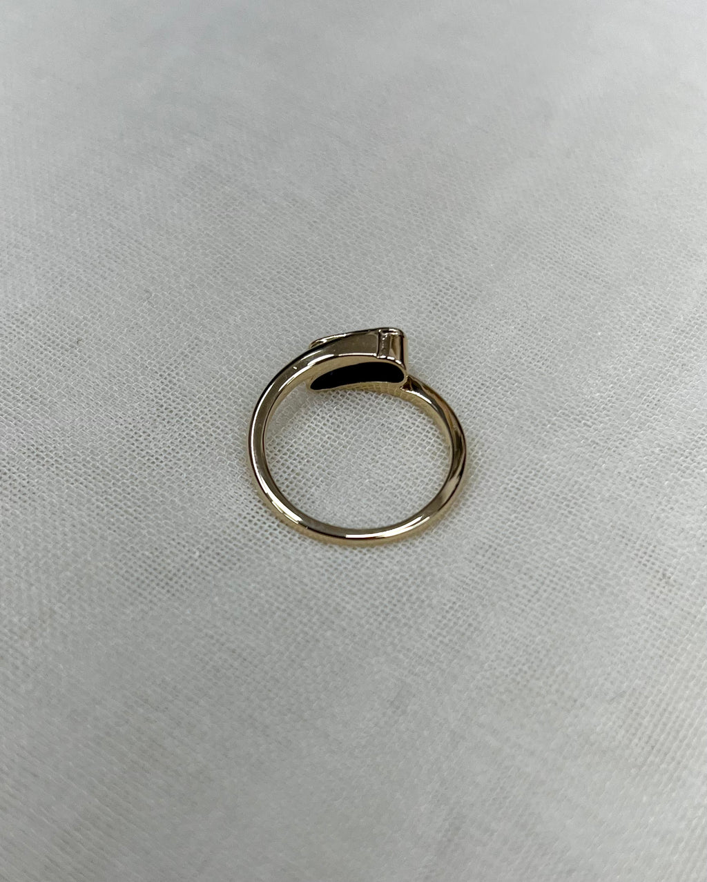 back view of gold ring resting on white fabric background