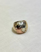 three tone gold ring with textured surface and leaf design on white fabric background 