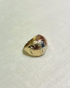 three tone gold ring with floral design on a white fabric background