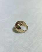 Gold ring with floral design on a white fabric background