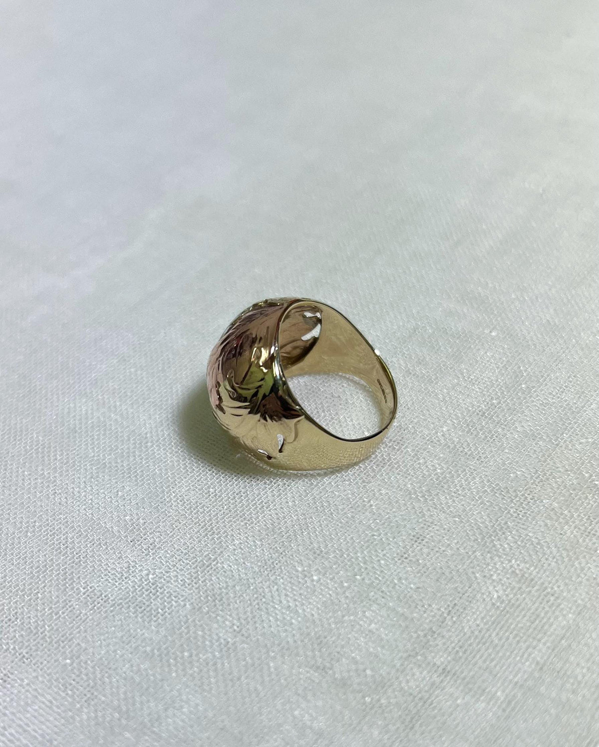 Gold ring with floral design on a white fabric background