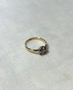 gold ring with sapphire and diamond cluster, on white fabric background 