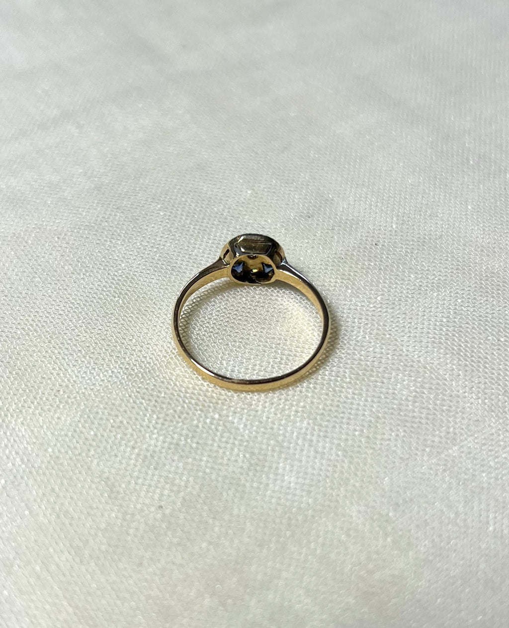 back view of gold ring, on white fabric background