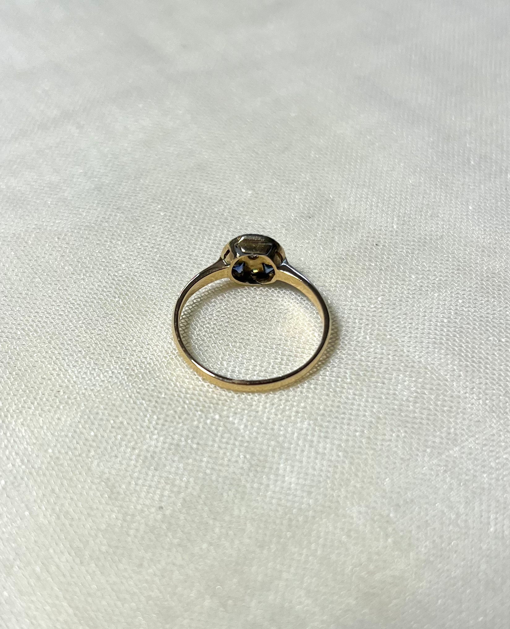 back view of gold ring, on white fabric background