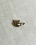 gold noahs ark charm on light fabric background