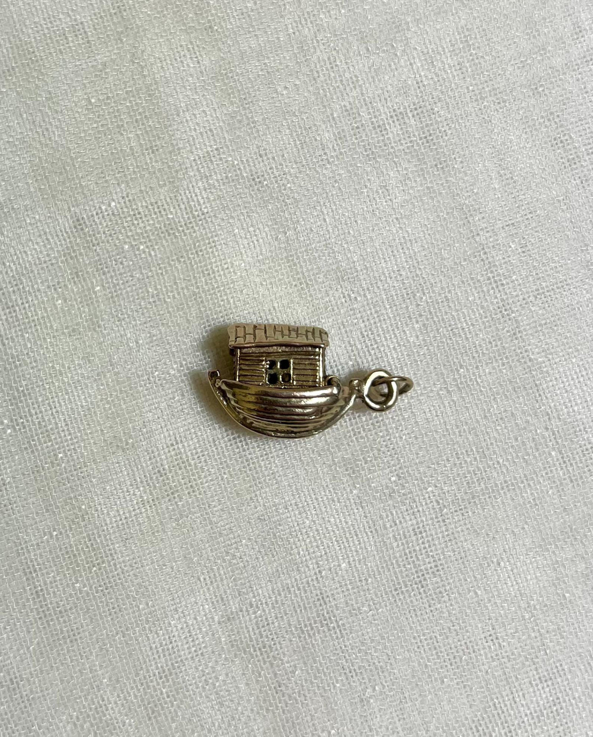 gold noahs ark charm on light fabric background