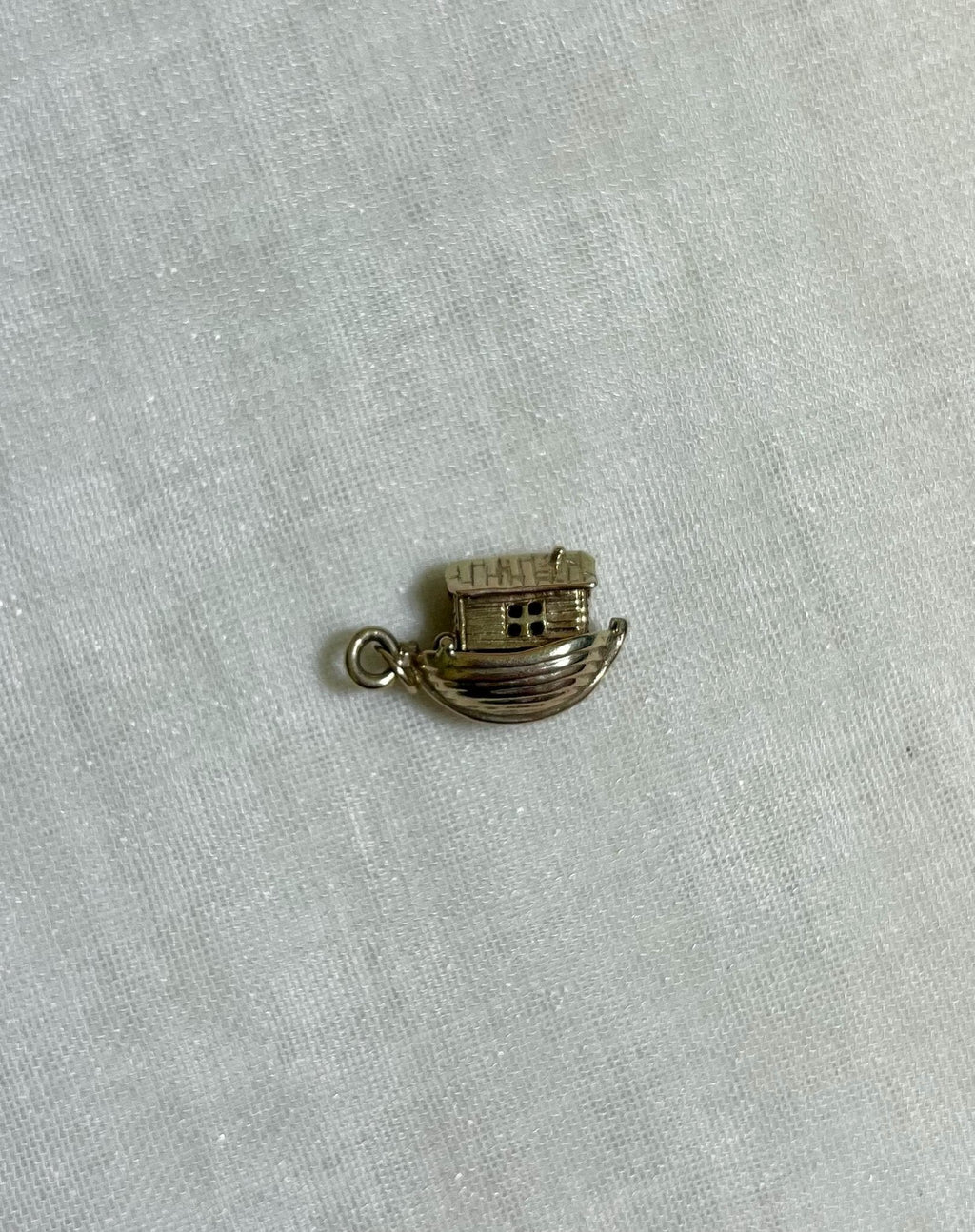 gold noahs ark boat charm on light fabric background 