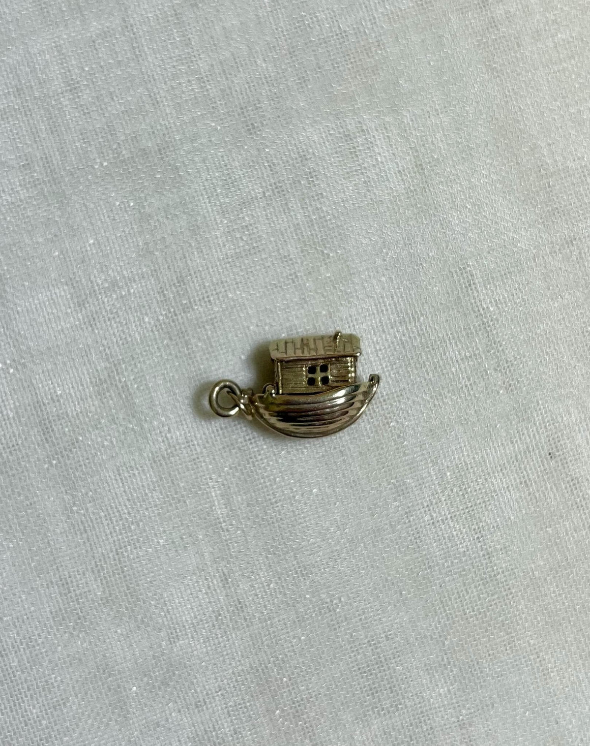 gold noahs ark boat charm on light fabric background 