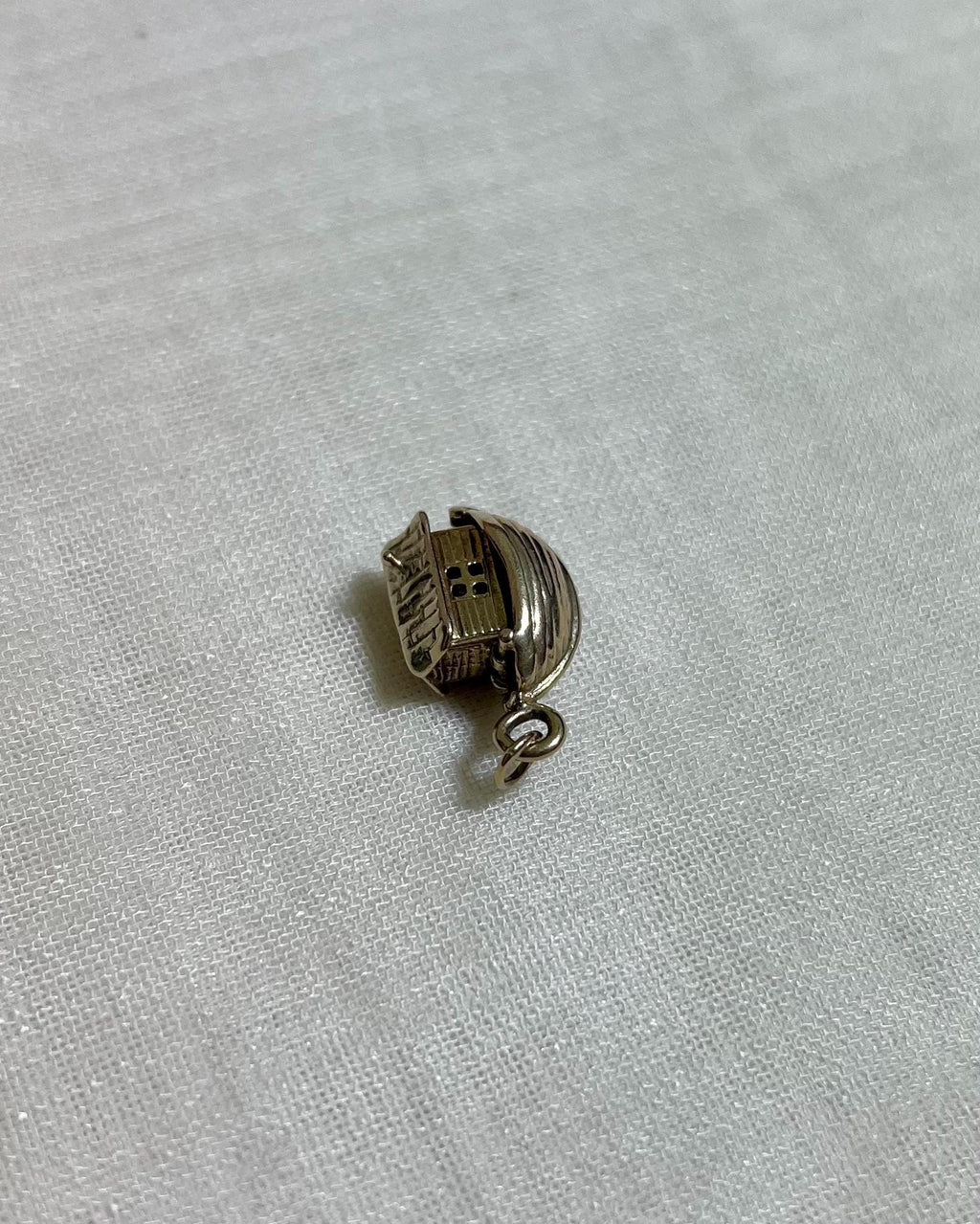 gold boat charm on light fabric background