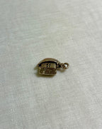 gold boat charm on light fabric background 