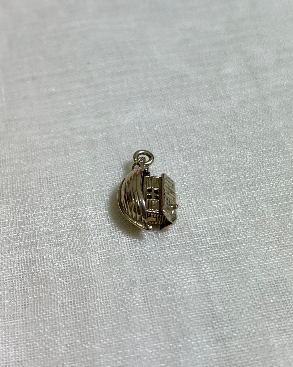 gold boat charm on light fabric background