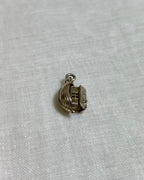 gold boat charm on light fabric background