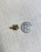 gold boat charm next to ten pence coin for size reference