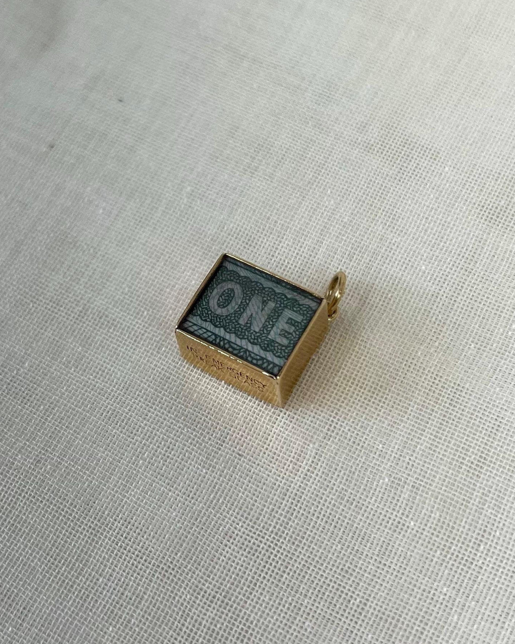 small square charm with one pound note inside, resting on white fabric background
