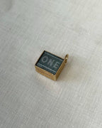 small square charm with one pound note inside, resting on white fabric background