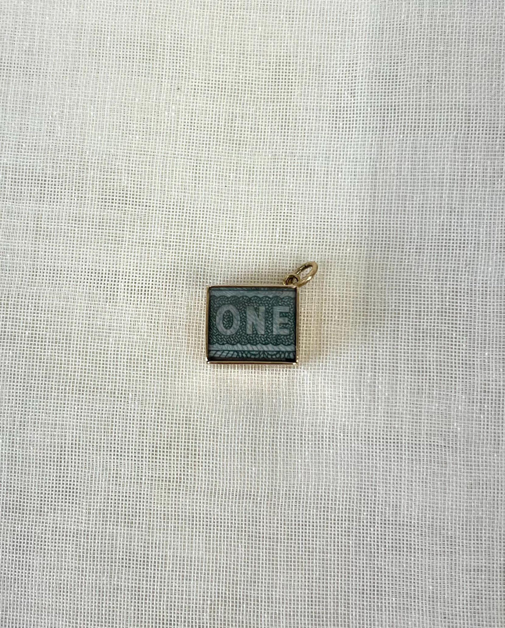 square gold charm with visible one pound note inside on white background 