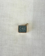 square gold charm with visible one pound note inside on white background 