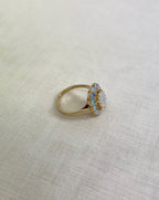 side view of gold ring with opal stones, resting on white fabric background 