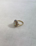 gold ring with opal halo cluster, resting on white fabric background