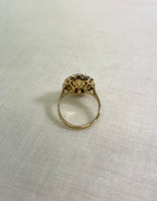 back view of gold ring, resting on white fabric background.