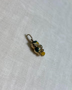 gold owl charm with green and yellow enamel accents on light cream fabric background