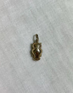 back of gold owl charm on light cream fabric background 