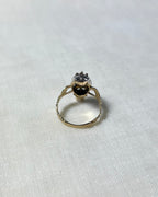 back view of gold stone set ring, on white fabric background
