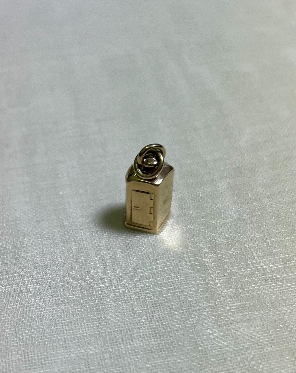 Small gold charm on a white fabric background