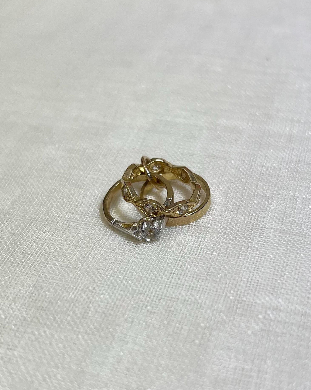 Gold ring with a clear cubic zirconia stone on a white fabric background