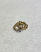 Gold ring with a clear cubic zirconia stone on a white fabric background