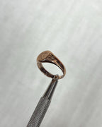 Rose gold ring with a engraved design on a light cream background