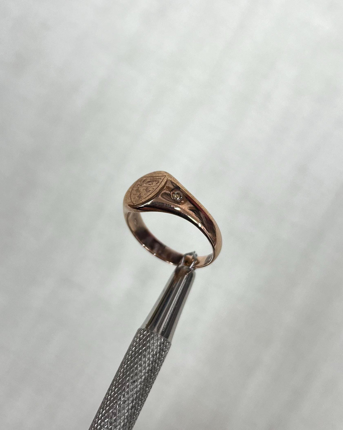 Rose gold ring with a engraved design on a light cream background