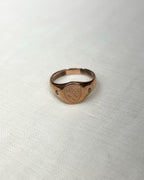 rose gold ring with shield crest engraving on white fabric background 