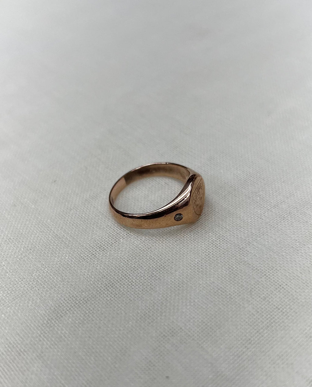 side view of rose gold ring on white fabric background