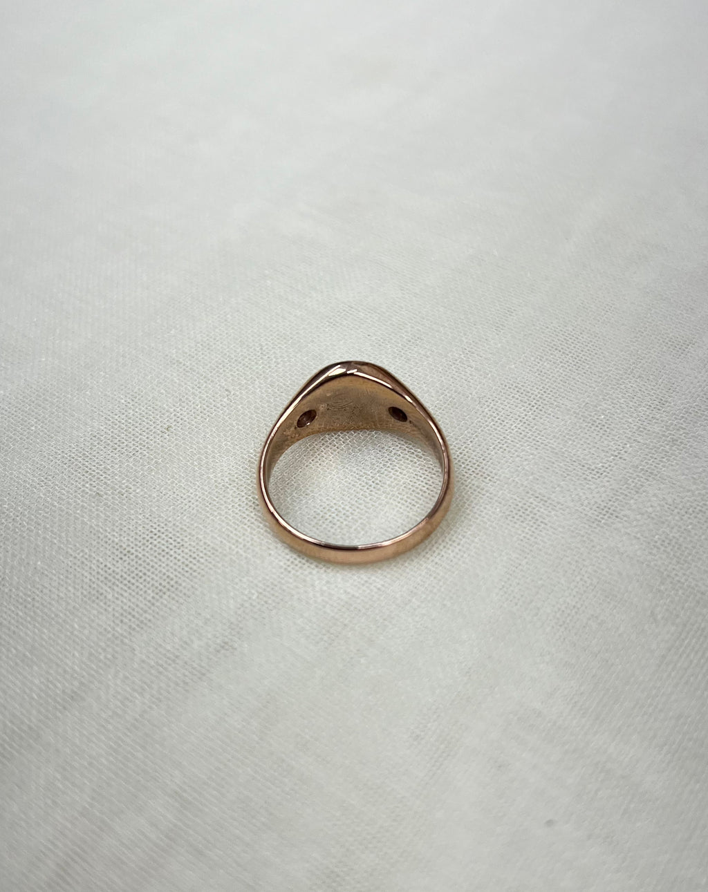 back view of rose gold ring on white fabric background 